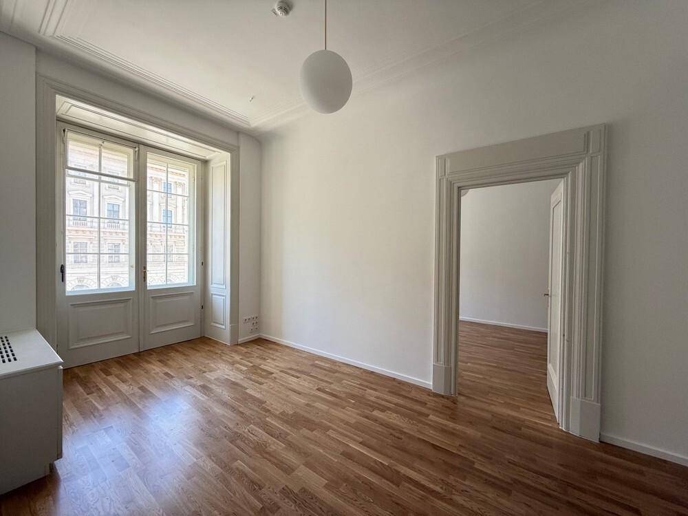 Geräumiges Büro mit Holzboden, hohen Decken und großen Fenstern, die den Raum erhellen.