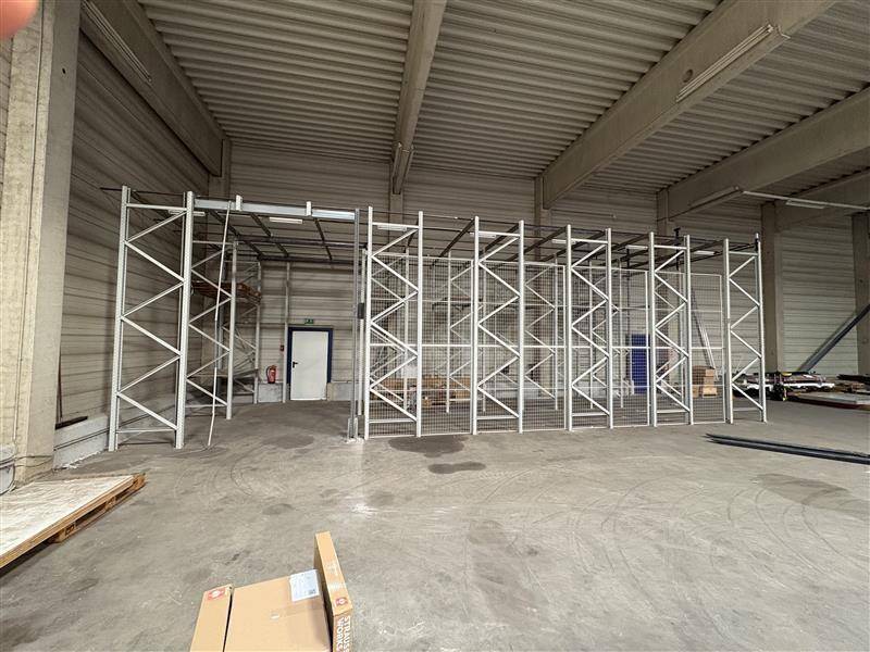 Leere Lagerhalle mit hohen Decken und modularen Metallregalsystemen bereit zur Bestückung.