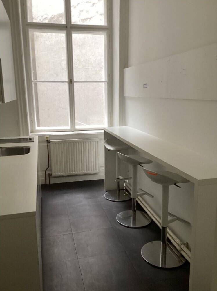 Küchenbereich mit Bartresen, Hockern, dunklen Fliesen und großem Fenster für Tageslicht.