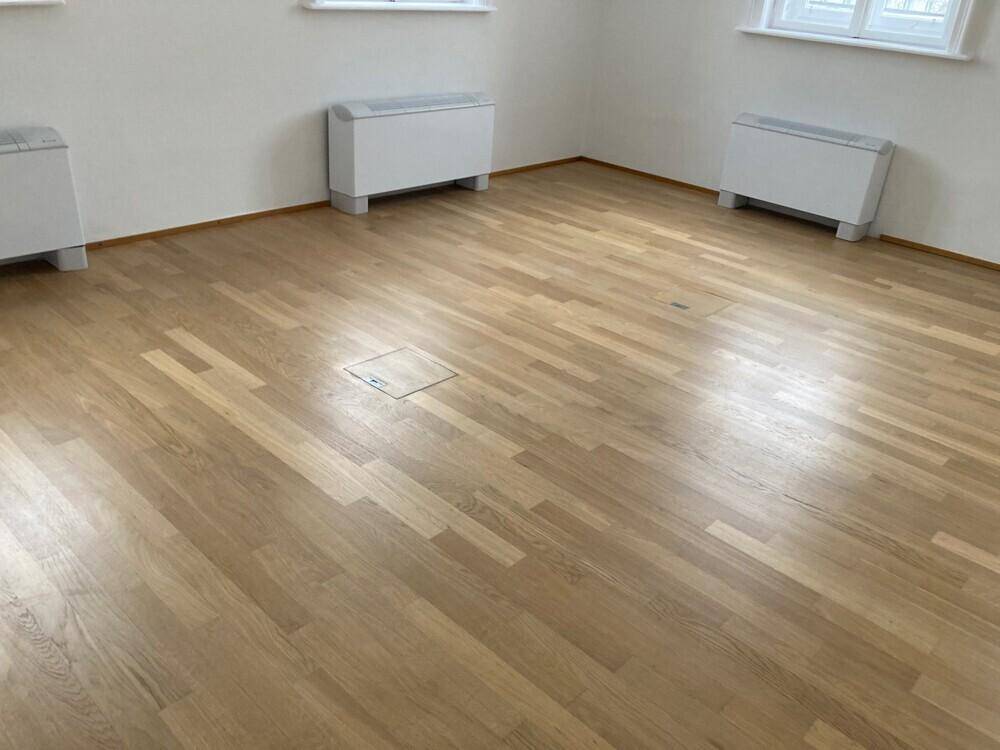Detailansicht des Holzboden in einem Büro mit Bodentanks für Anschlüsse.