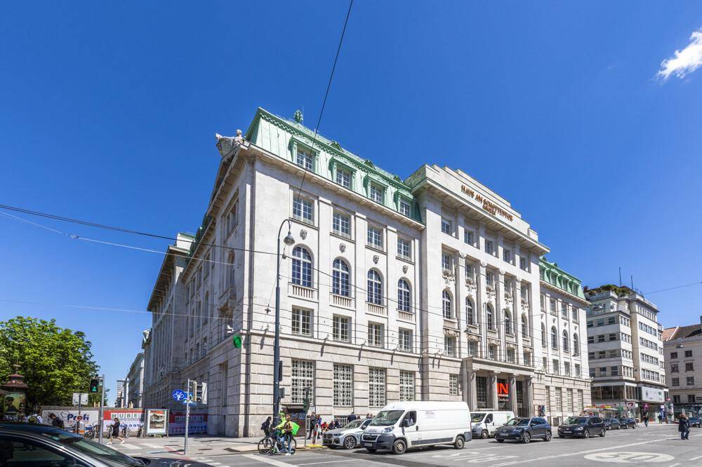 Weitläufige Ansicht des historischen Gebäudes mit seiner prächtigen Fassade und dem grünen Mansarddach in der Stadt.