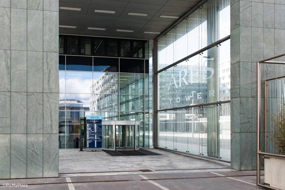 Eingangsbereich eines modernen Bürogebäudes mit großer Glasfassade und automatischen Drehtüren.