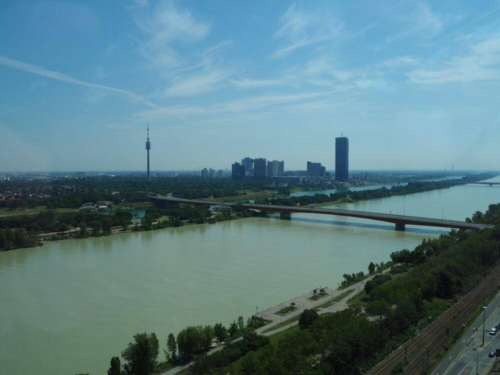 Weitläufige Luftaufnahme einer Stadtlandschaft mit Fluss, Brücken und Hochhäusern unter blauem Himmel.