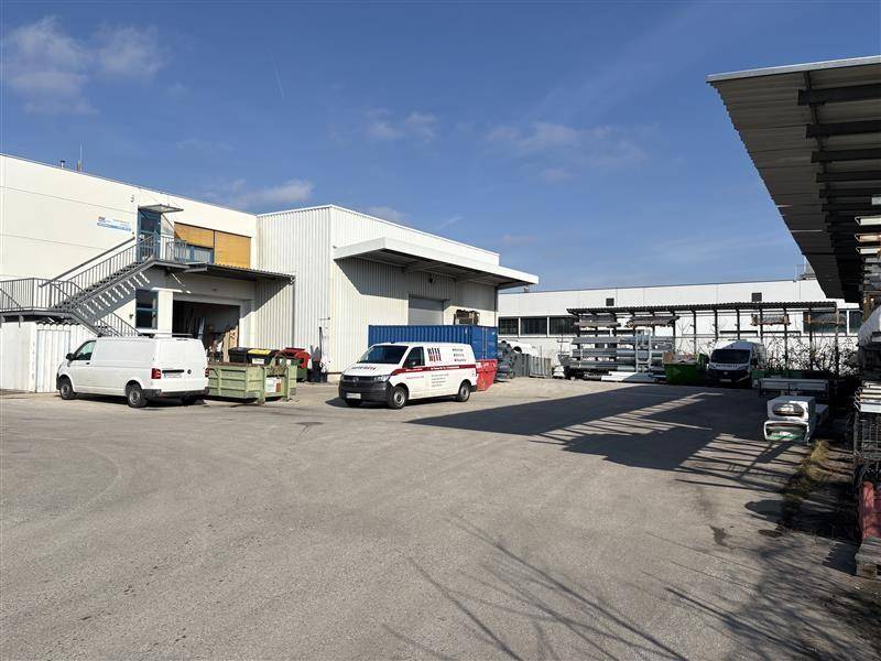 Außenansicht eines Industrieareals mit Lieferwagen, Laderampen und Lagerflächen.