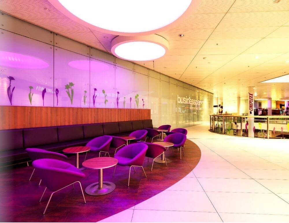 Lounge-Bereich in einem Einkaufszentrum mit farbiger Beleuchtung und modernen Sitzgelegenheiten.