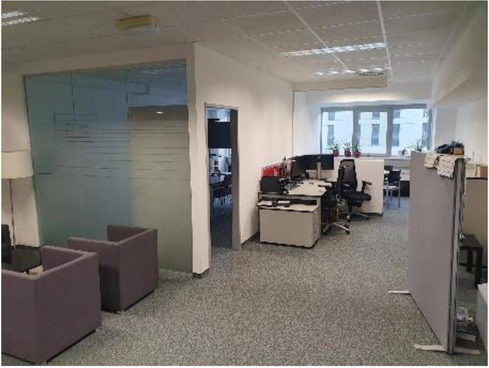 Bürofläche mit modernen Arbeitsplätzen, Trennwänden aus Milchglas und bequemen Sitzgelegenheiten.