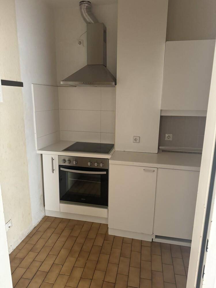 Kleine Einbauküche mit weißen Schränken, Induktionskochfeld, Backofen und Dunstabzugshaube.