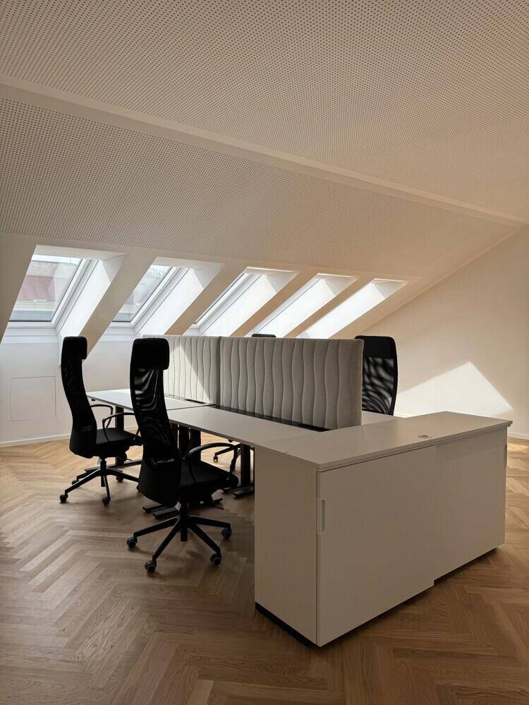 Helles Großraumbüro mit modernen Schreibtischen, ergonomischen Stühlen und Fischgrätparkettboden.