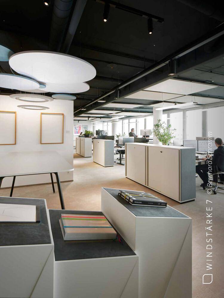 Helles Großraumbüro mit modernen Möbeln, Kunstwerken und ergonomischen Arbeitsplätzen.
