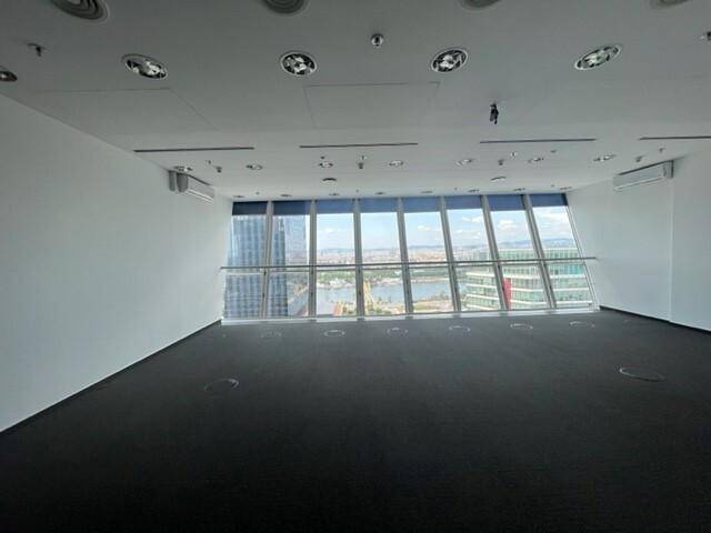 Heller Büroraum mit großen Fenstern, die einen weiten Blick auf die Stadt und das Wasser bieten.