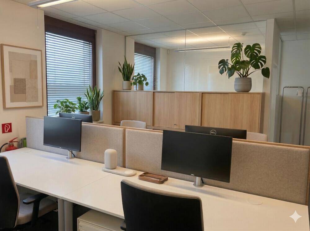 Moderner Büroraum mit mehreren Arbeitsplätzen, Trennwänden und Pflanzen zur Dekoration.