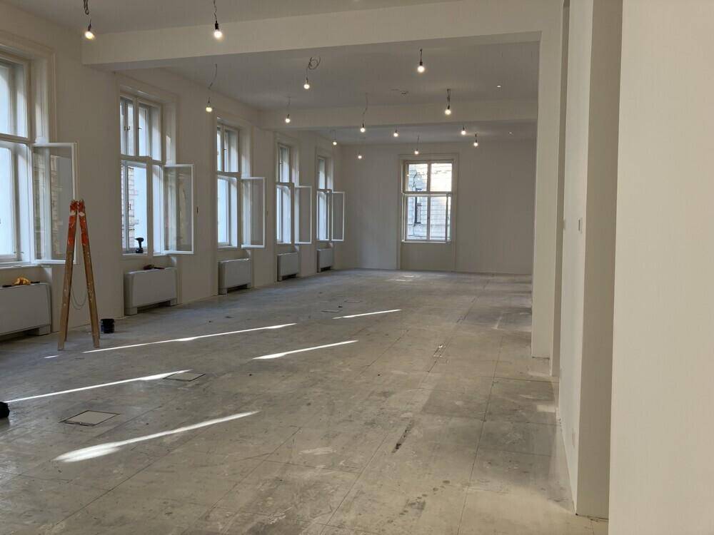 Heller, weitläufiger Büroraum mit zahlreichen Fenstern, die viel Tageslicht hereinlassen, und hohen Decken.