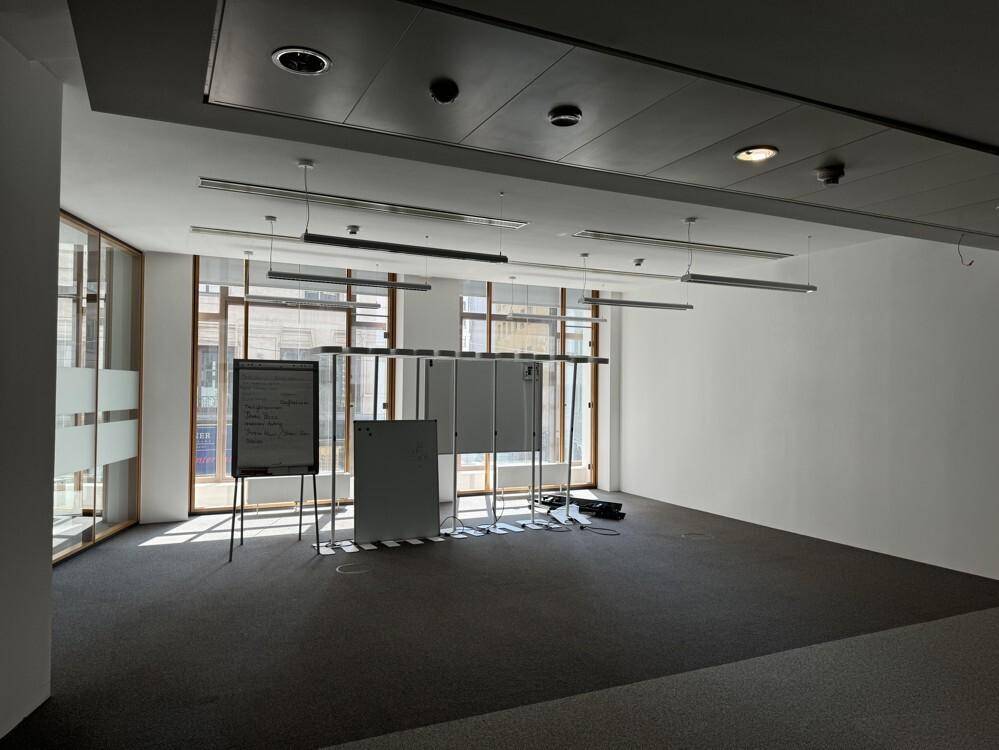 Heller Konferenzraum mit Teppichboden, großen Fenstern und Whiteboards, ideal für Besprechungen.