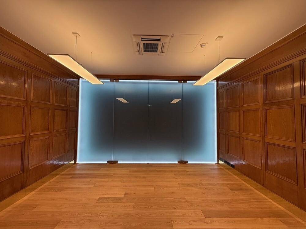 Modernes Büro mit Holzvertäfelung, Holzboden und einer Milchglaswand für Privatsphäre.