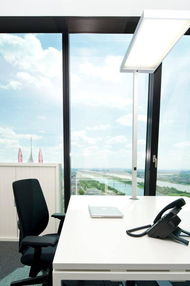 Detailansicht eines Büroschreibtisches mit Laptop und Telefon, mit weitem Blick aus dem Fenster.