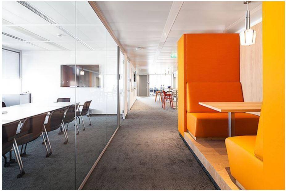 Moderner Bürobereich mit orangefarbenen Sitzgelegenheiten und Glaswänden.