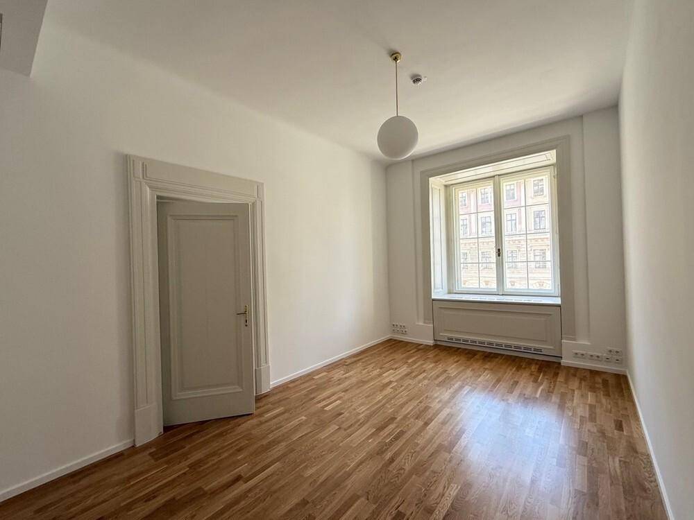 Helles Büro mit Holzboden, weißen Wänden und einem großen Fenster, das viel Licht hereinlässt.