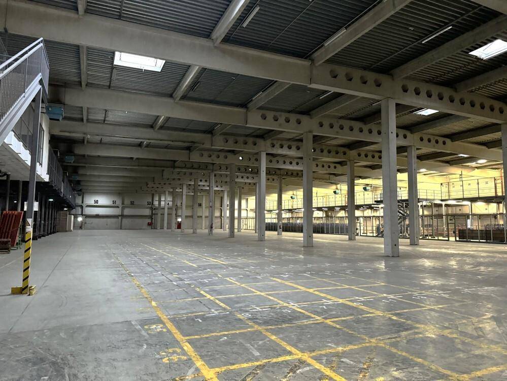 Geräumige Lagerhalle mit hoher Decke, Betonboden und sichtbaren Stahlträgern, bereit zur Nutzung.