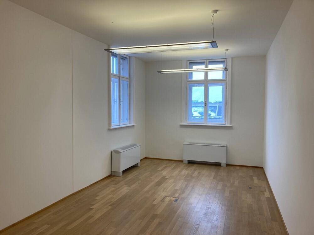Helles Büro mit Holzboden und zwei großen Fenstern, die eine weite Aussicht bieten.