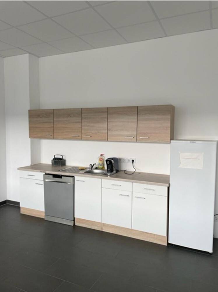 Funktionale Küchenzeile mit Spülmaschine, Kühlschrank und einer Kombination aus Holz- und weißen Schränken.