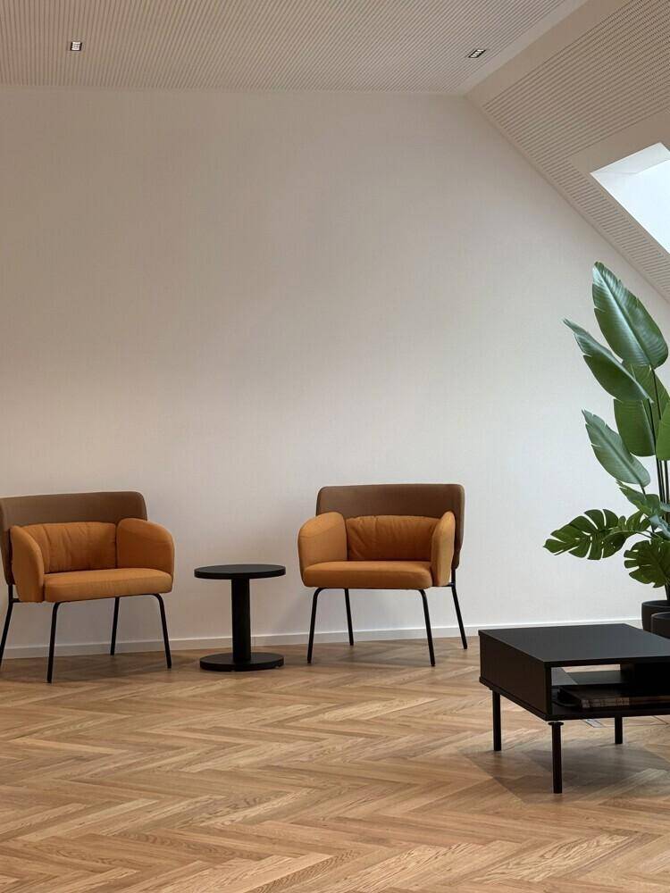 Heller Lounge-Bereich mit zwei modernen Sesseln, einem kleinen Beistelltisch und einer Zimmerpflanze.