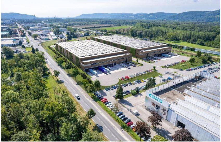 Weitläufige Luftaufnahme des Industrieparks mit modernen Lagerhallen, umgeben von Natur und weiteren Gewerbegebieten.