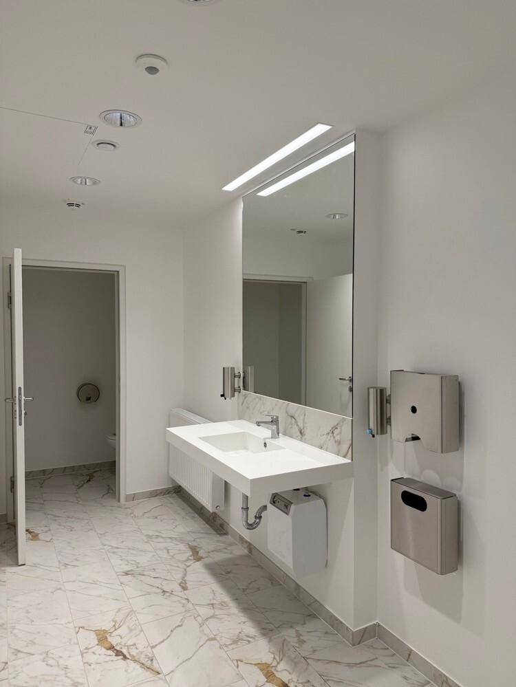 Modernes Badezimmer mit Marmorfliesen, Doppelwaschbecken und großem Spiegel, sehr gepflegt.