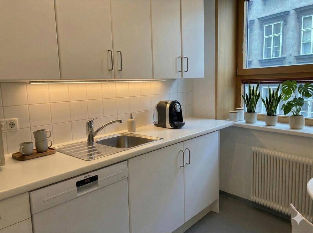 Funktionale Küche mit weißen Schränken, Spülmaschine und Kaffeemaschine, ideal für den Büroalltag.