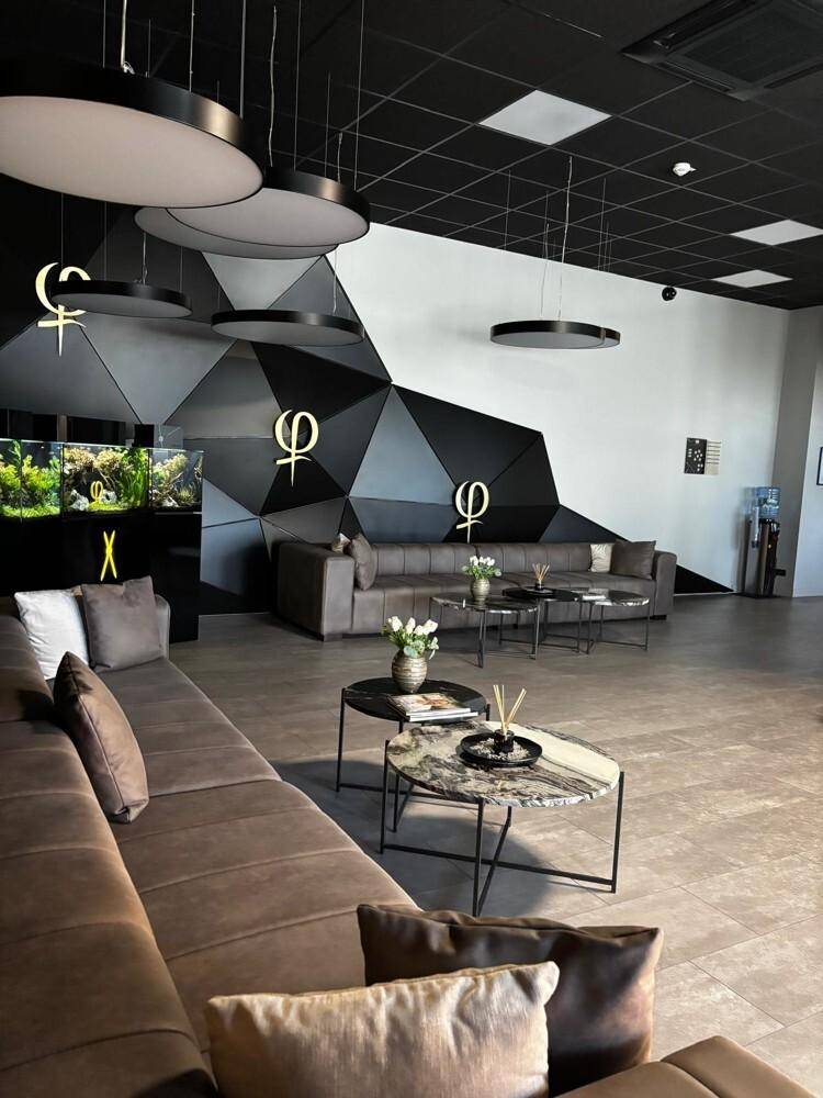 Gemütlicher Loungebereich mit bequemen Sofas, stilvollen Couchtischen und einer auffälligen geometrischen Wandgestaltung.