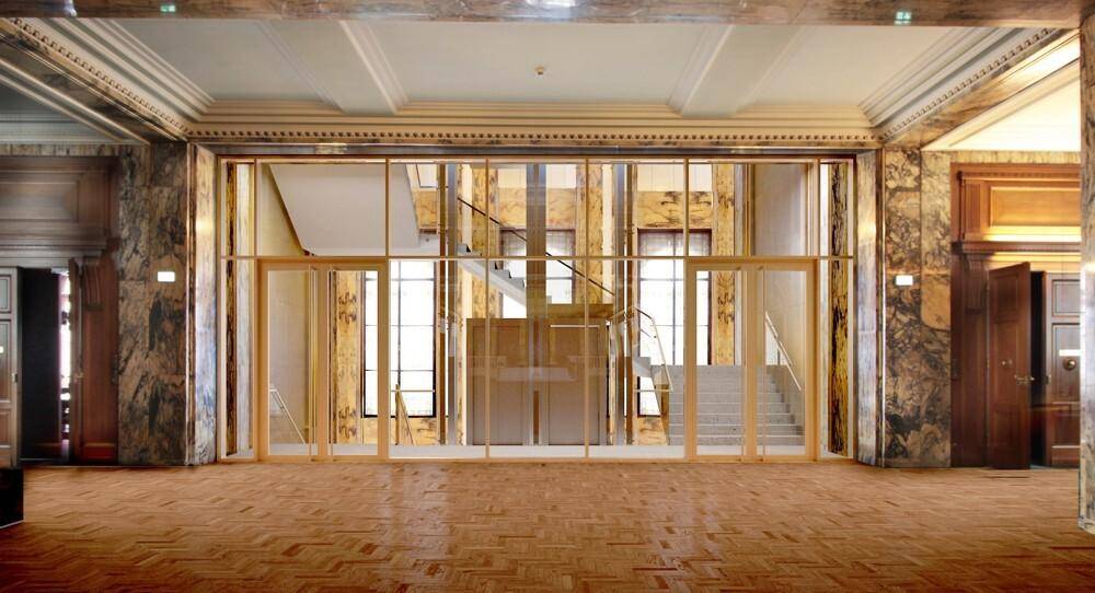 Repräsentativer Eingangsbereich mit Fischgrätparkett, Marmorwänden und einer eleganten Glasabtrennung zum Treppenhaus.