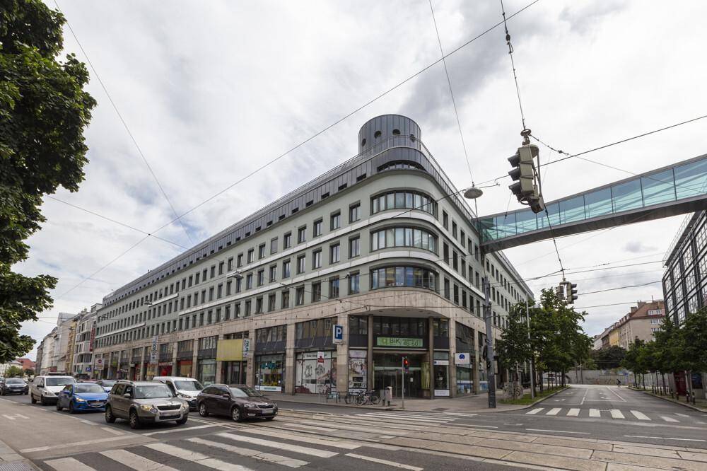 Das moderne Geschäftsgebäude mit seiner geschwungenen Fassade und vielen Fenstern, umgeben von städtischem Verkehr.