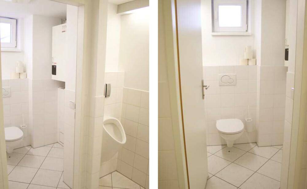 Helle Toilettenanlage mit weißen Fliesen, Fenstern und Urinal.