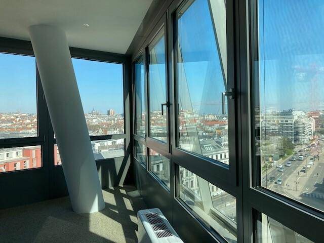 Helle Büroecke mit großen, schrägen Fenstern, die einen weiten Blick über die Stadt ermöglichen.