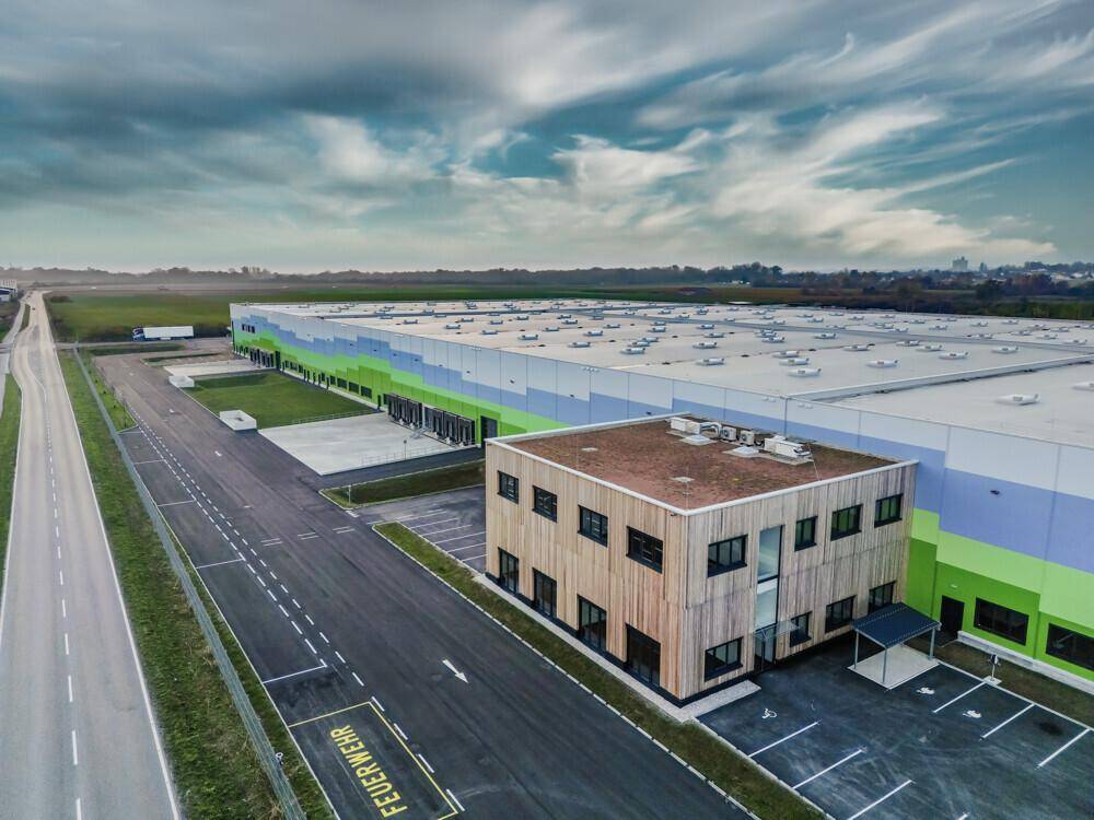 Luftaufnahme des Logistikzentrums mit einem separaten Bürogebäude und Zufahrtsstraßen.