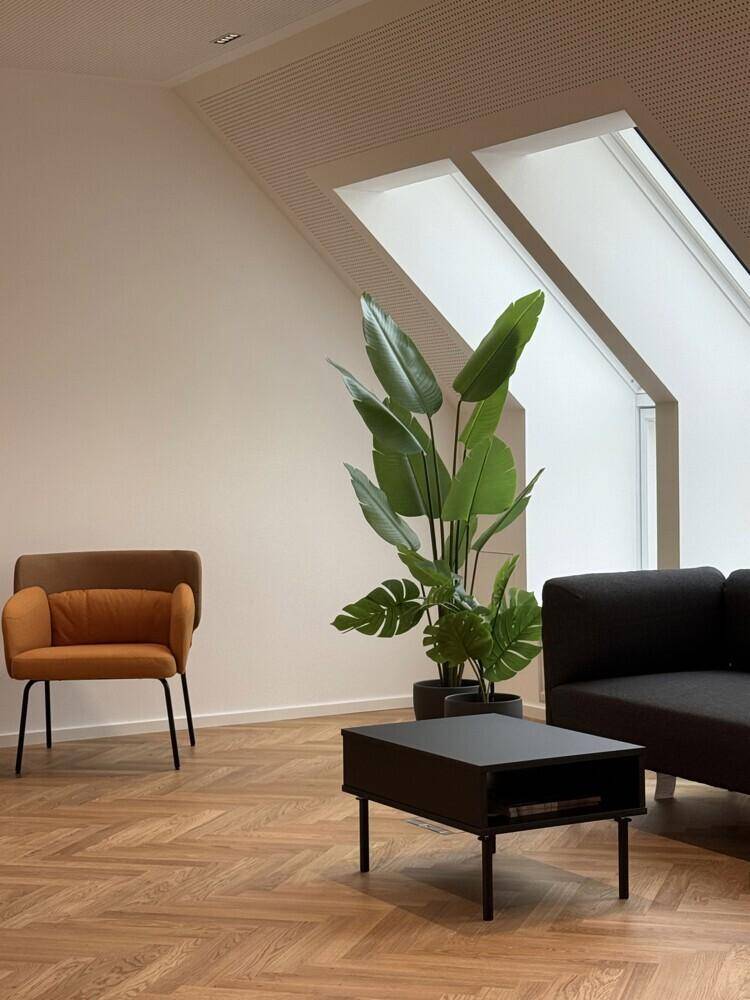 Gemütlicher Lounge-Bereich mit bequemen Sesseln, einem Couchtisch und einer großen Zimmerpflanze.