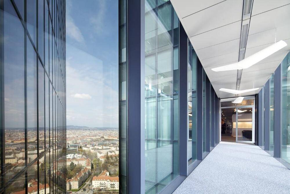 Moderner Bürogang mit raumhohen Fenstern und weitem Blick über die Stadtlandschaft.
