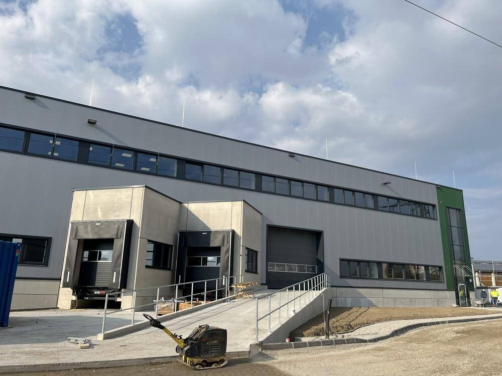 Die Außenseite des Industriegebäudes mit Laderampen, einer Zufahrtsrampe und einem modernen Eingangsbereich.