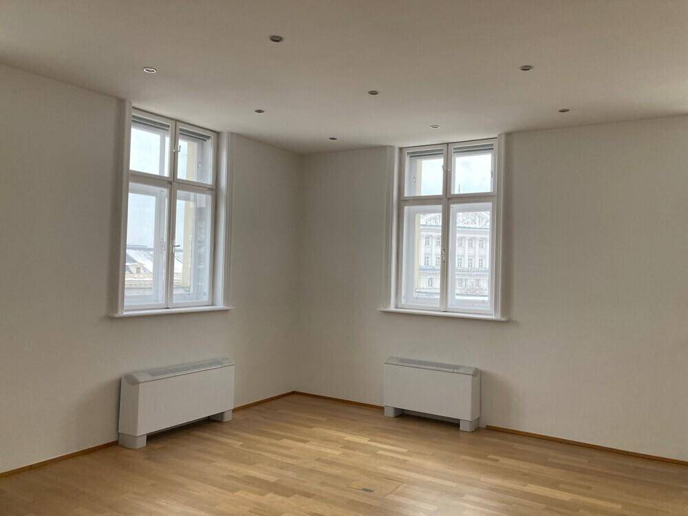 Helles Büro mit Holzboden und zwei großen Fenstern, die eine weite Aussicht bieten.