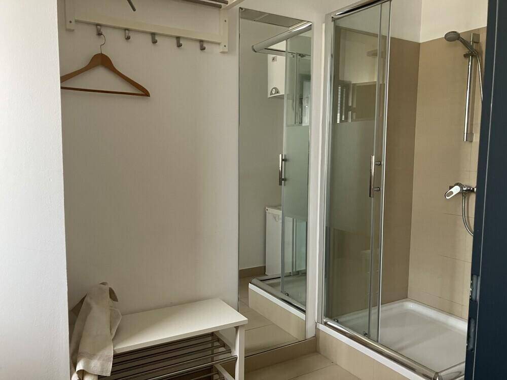 Badezimmer mit Duschkabine, großem Spiegel und einer Garderobe mit Schuhablage.