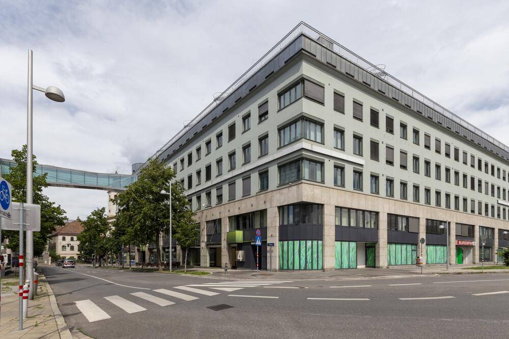 Ansicht des modernen Gebäudes von der Straßenseite, mit Fußgängerüberweg und Fahrradweg.