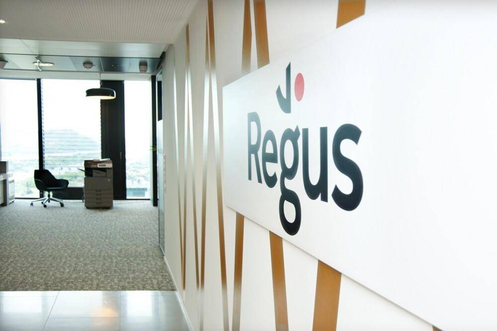 Flur mit Regus-Logo, der zu einem hellen Bürobereich mit weitem Ausblick führt.