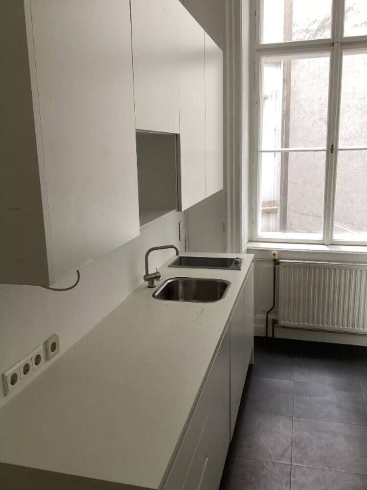 Moderne Küchenzeile mit weißen Schränken, Doppelspüle und dunklen Fliesenböden.