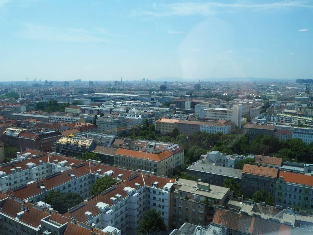 Panoramablick über eine dicht bebaute Stadt mit zahlreichen Gebäuden und roten Dächern unter klarem Himmel.