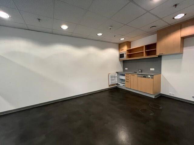 Funktionale Teeküche mit hellen Holzschränken, Spüle, Kühlschrank und Mikrowelle in einem Bürobereich.