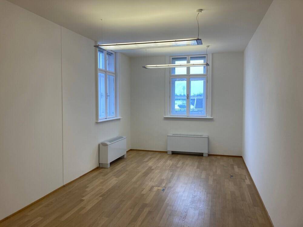 Helles Büro mit Holzboden und zwei großen Fenstern, die eine weite Aussicht bieten.