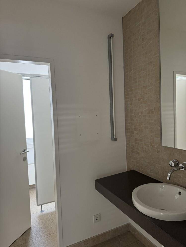 Modernes Badezimmer mit einem Waschbecken, großem Spiegel und einer eleganten Fliesenwand.