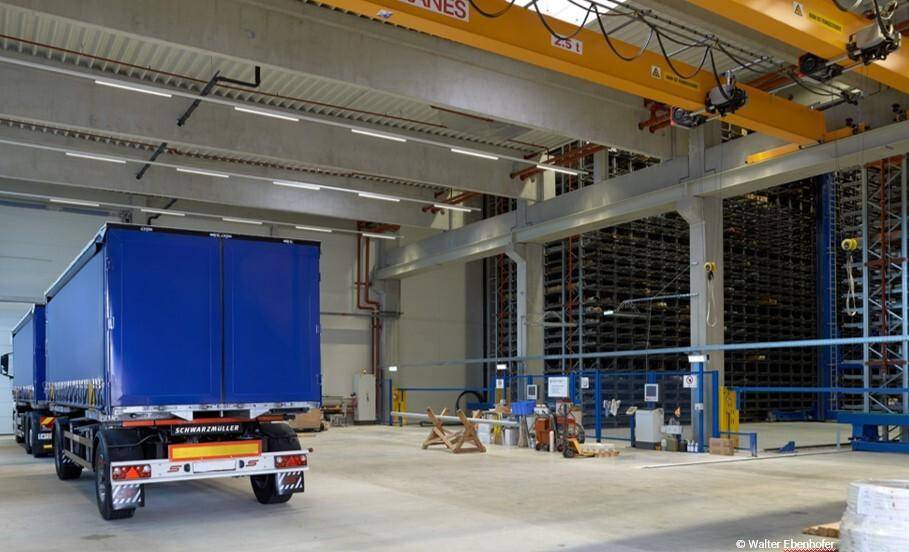 Geräumige Lagerhalle mit einem LKW, Krananlagen und hohen Decken für Logistik und Materialtransport.