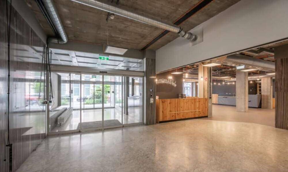 Eingangsbereich mit Rezeption, automatischen Glastüren und Blick in den offenen Bürobereich.