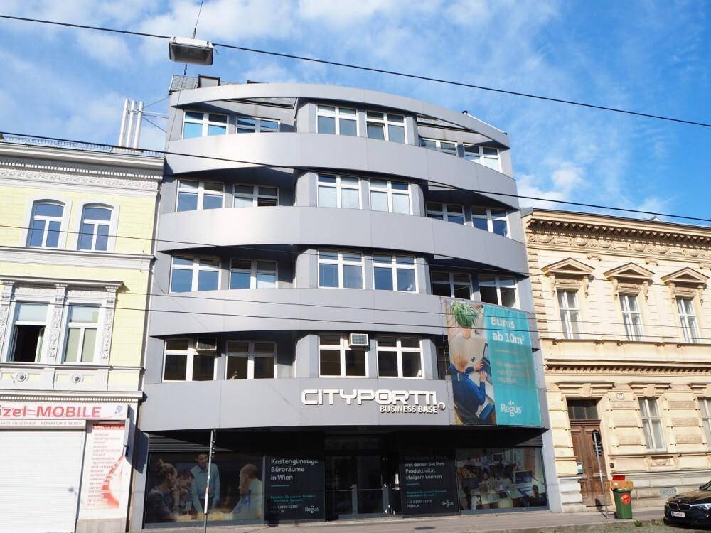 Ansicht des modernen Geschäftsgebäudes mit markanter grauer Fassade und vielen Fenstern unter blauem Himmel.