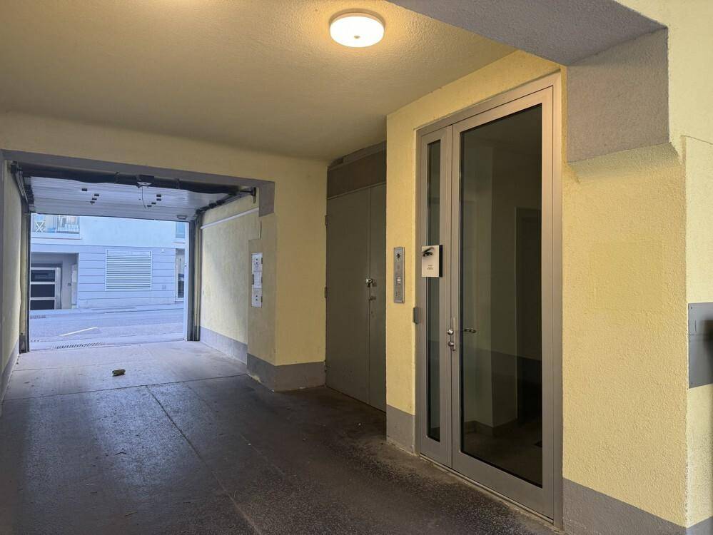 Eingangsbereich des Gebäudes mit Glastür, Aufzug und Durchgang zum Hof oder zur Straße.